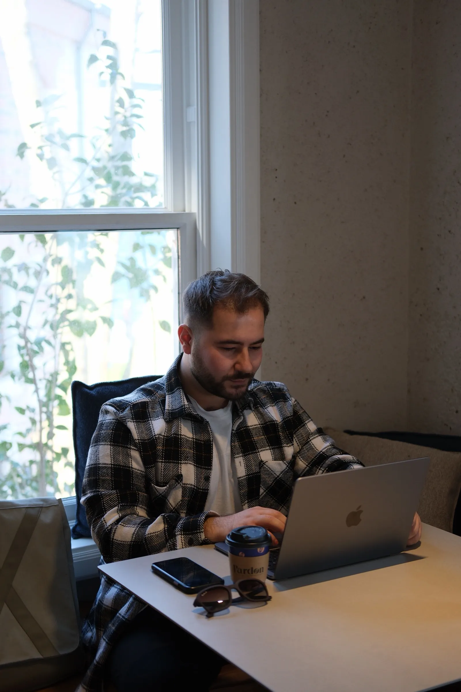 A man on a video counseling session on his laptop by a sunny window at home